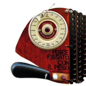 Dettaglio del quadrante di bilancia da cucina vintage integrato come occhio nella scultura di pesce in legno rosso con la scritta PESCE FISSATO CON IL PESO