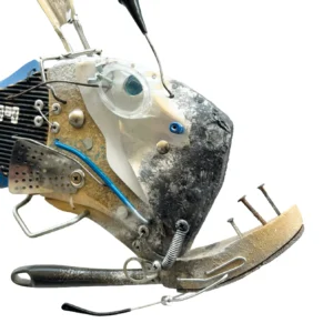 Dettaglio della testa del pesce abissale in metallo e plastica con occhio sporgente trasparente e mandibola curva ricoperta da chiodi rustici