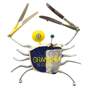 Scultura da parete a forma di granchio con corpo in legno blu e giallo, grandi chele in metallo e gambe metalliche curve