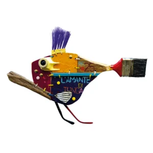 Scultura a parete in legno e materiali di recupero raffigurante un pesce con cresta di pennello viola, coda da pennello e la scritta L'AMANTE DI TONGA P.F. 25