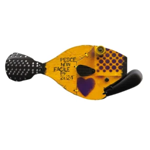 Scultura a parete a forma di pesce in legno giallo con motivi a pallini viola, coda metallica traforata e la scritta PESCE NON FACILE P.F. 2024