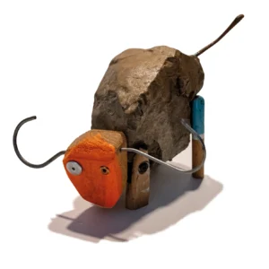 Un'opera d'arte cinetica a tecnica mista di un toro stilizzato, creata assemblando una grossa pietra naturale come corpo, pezzi di legno grezzo per le zampe (una dipinta di blu), un blocco di legno dipinto di arancione brillante per la faccia con un occhio a cerchio metallico, e fili metallici curvati per le corna e la coda. "toro claro"