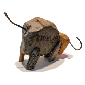Una scultura a tecnica mista che raffigura un toro stilizzato, con una grande pietra naturale che funge da corpo. La pietra è sostenuta da zampe di legno grezzo di diverse dimensioni e forme. Un pezzo di legno non dipinto costituisce la parte posteriore, mentre fili metallici curvati formano le corna e la coda. La scultura è del 2015 "toro claro".