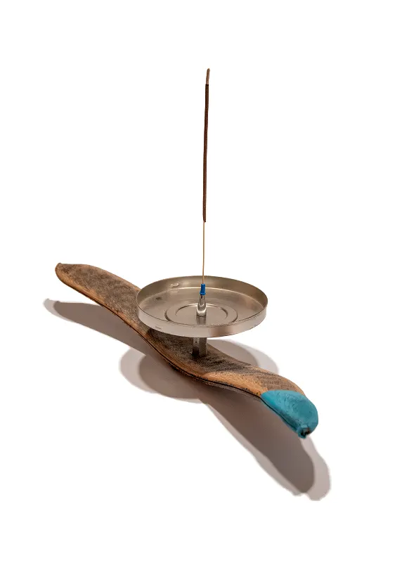 porta-incenso-cabeza-azul Portaincenso artigianale minimalista in legno di carruba e metallo con finitura azzurra sulla punta su sfondo bianco.