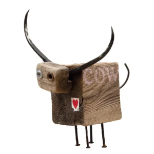 Scultura in blocco di legno a forma di mucca con corna in ferro battuto, zampe in chiodi e la scritta COW