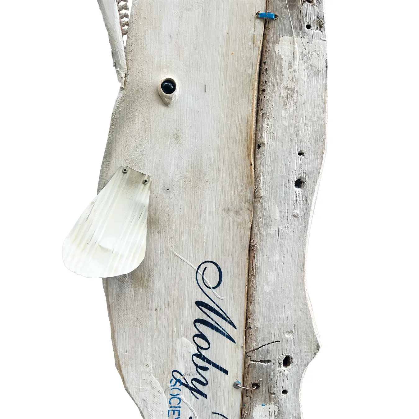 Dettaglio del tronco in legno sbiancato della scultura Moby Dick Socievole con pinna in metallo chiaro e dicitura stilizzata Moby Socievole