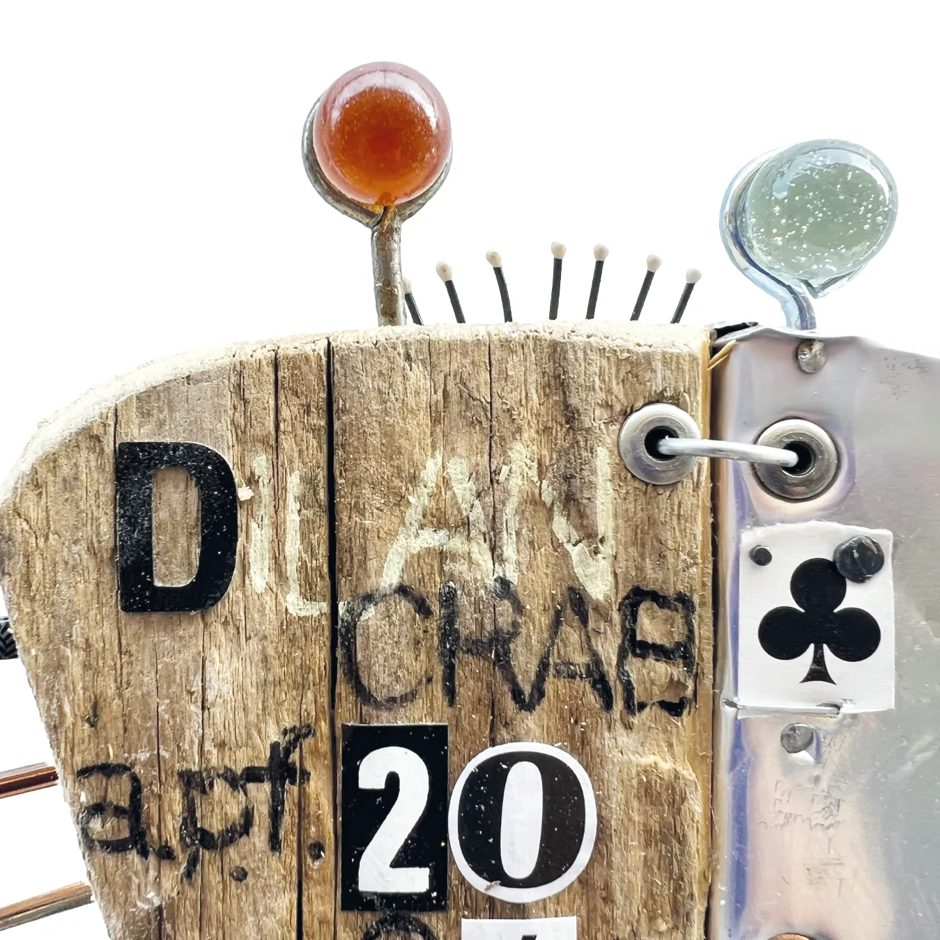 Dettaglio del corpo della scultura Dilan Crab in legno con etichetta di carta da gioco asso di fiori, occhi in vetro e la scritta DILAN CRAB APF 2026